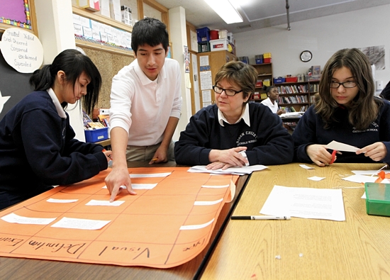 Teacher Gail McCollum, second from right, helps eighth-graders Yeneira Rosario, left, Diego Romero and Argentina Lerma during reading/literature class at Risen Christ School in Minneapolis. Under a new proposal, students at the school would become bilingual in English and Spanish. Dave Hrbacek / The Catholic Spirit