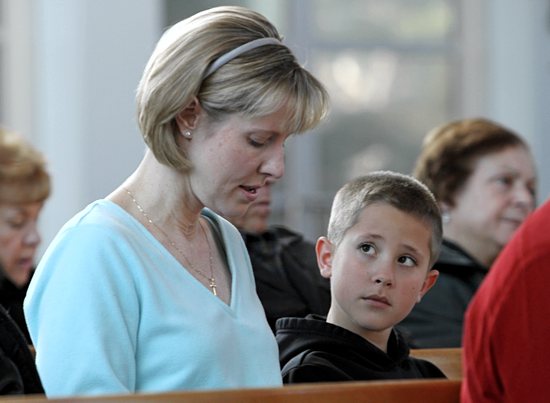 Brad Stankiewicz, 8, looks at his mother, Kathy, as she prays during a special Mass at Holy Cross Church in Nesconset, N.Y., Dec. 28 for the 26 students and staff members killed two weeks earlier at Sandy Hook Elementary School in Newtown, Conn. The Mass coincided with the feast of the Holy Innocents. CNS photo / Gregory A. Shemitz