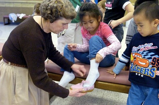 Mary Jo Copeland of Sharing and Caring Hands helps 7-year-old Mang Vang pick a new pair of shoes at Mary's Place in Minneapolis in this 2007 photo. (Dianne Towalski / The Catholic Spirit)