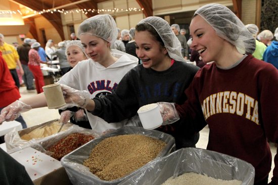 Above, from left, Emma Johnson, Reegan Patnode, Madison Matthews and Taylor Bergum of St. Patrick of Inver Grove Heights scoop ingredients as they prepare meals for Feed My Starving Children March 6. On four consecutive days last week, parishioners of all ages joined volunteers from other local churches to prepare meals for the Twin Cities organization, which packs and ships food to needy children around the world. They packed a total of 54,000 meals. Dave Hrbacek / The Catholic Spirit