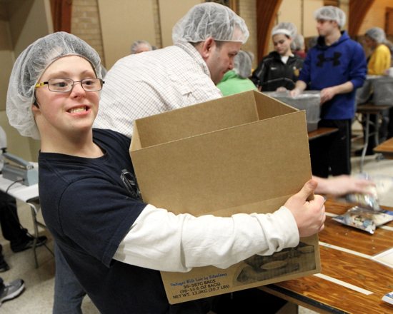Kyle Laundry of St. Patrick removes a finished box of packed meals from the prep station. He was part of a group of 100 faith formation students who participated. Dave Hrbacek / The Catholic Spirit