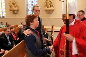 Matthew Brown greets Bishop Lee Piché after being confirmed during a Mass April 22 at St. Mary in Stillwater. His scheduled confirmation was moved up to accommodate the failing health of his sponsor, Zach Sobiech, center. (Dave Hrbacek/The Catholic Spirit)