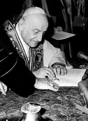 Pope John XXIII signs his encyclical “Pacem in Terris” (“Peace on Earth”) at the Vatican in this 1963 file photo.  CNS photo 