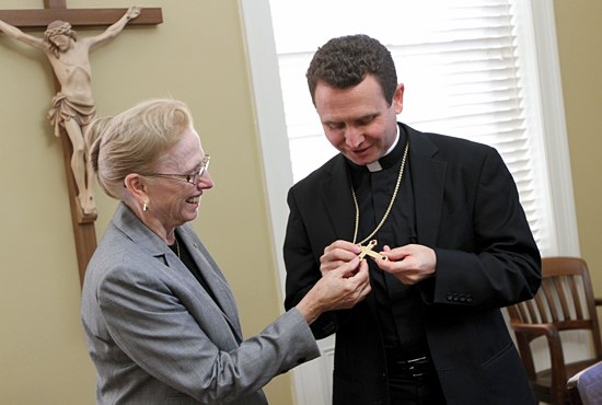 Bishop-elect Andrew Cozzens shows his mother, Judy, a pectoral cross given to him by Archbishop John Nienstedt. (Dave Hrbacek/The Catholic Spirit)