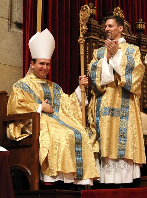 After receiving his crosier and miter, Bishop Cozzens is applauded by the congregation, including Deacon Joseph Michalak, right.