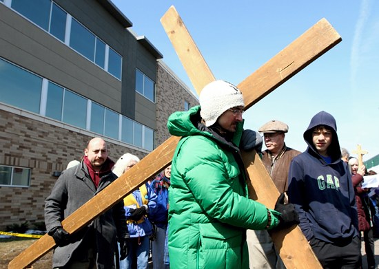 Nicholas Listi carries the cross during the event. He is a postulant with the Franciscan Brothers of Peace in St. Paul. (Dave Hrbacek/The Catholic Spirit)