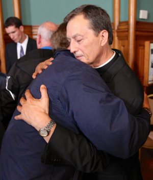 Father Charles Lachowitzer hugs an abuse survivor after the press conference. Dave Hrbacek/The Catholic Spirit
