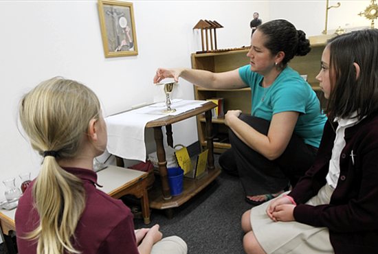 Teacher Carolyn Kohlhaas, center, shows a chalice to fifth-graders Sarah Turner, left, and Maia Irwin at the gestures altar in the Catechesis of the Good Shepherd atrium. Dave Hrbacek/The Catholic Spirit