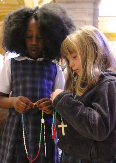 From left, second-grader Jazmine Sombai and kindergartner Lizzy Churchill pray during the Children's Rosary Pilgrimage Oct. 7 at the Cathedral of St. Paul in St. Paul. Catholic schools from across the Archdiocese of St. Paul and Minneapolis gathered for the annual event. Dave Hrbacek/The Catholic Spirit