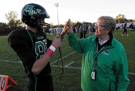 Benedictine Sister Linda Soler gives a high five to Hill-Murray senior Garrett Kaelin before a game against Simley Oct. 2. Kaelin, a kicker, is holding Sister Linda’s “football rosary,” which she carries with her while walking the field before games to cheer on and pray with the players. Dave Hrbacek/ The Catholic Spirit