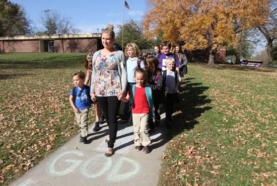 Kindergarten teacher Becky McGillivray of St. Dominic School in Northfield walks students, including kindergartners Ben Jerdee, left, and Hailey Berg to their buses at the end of the school day Oct. 19. The school serves families in Northfield and the surrounding rural area. Dave Hrbacek/The Catholic Spirit