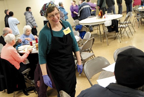Pat Haas takes time out from serving the meal and supervising volunteers to greet guests at the weekly Thursday night dinner Nov. 19 at Mary, Mother of the Church in Burnsville. Dave Hrbacek/The Catholic Spirit