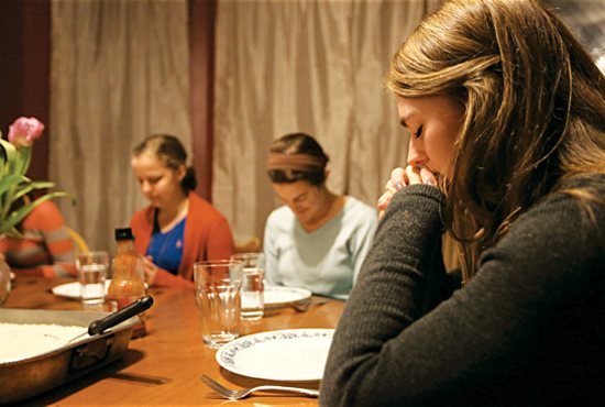 Kayla Lynch, right, joins in prayer before dinner along with other members of an SPO women’s household near the University of Minnesota. Joining her are Ariel Garsow, left, and Alex Bosch. Dave Hrbacek/ The Catholic Spirit