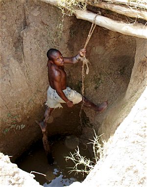  A Tanzanian man fetches water in a surface well hole, which the Tanzania Life Project made possible. Courtesy Jim and Katie Vanderheyden