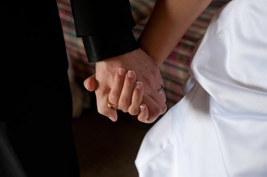 A groom and bride hold hands on their wedding day. CNS