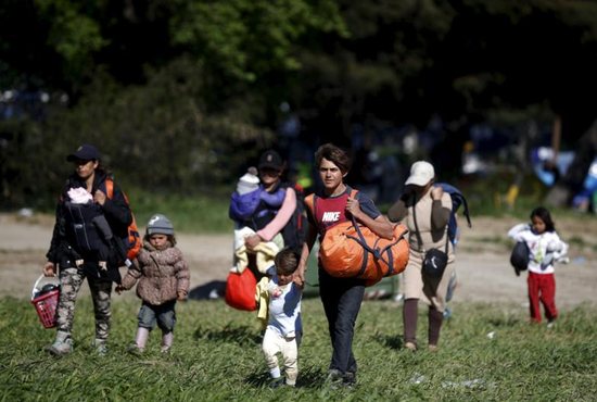 People walk toward a bus April 12 at a makeshift camp for refugees and migrants at the Greek-Macedonian border near the village of Idomeni, Greece. Pope Francis asked Christians to pray for him before embarking on a one-day visit to the Greek island of Lesbos April 16. CNS photo/Stoyan Nenov, Reuters