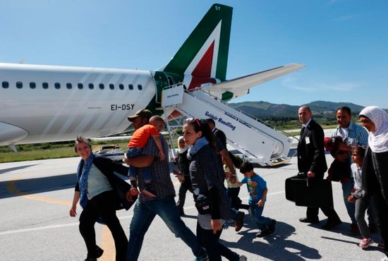 Refugees walk to board Pope Francis' plane to Rome at the international airport in Mytilene on the island of Lesbos, Greece, April 16, 2016. The pope brought 12 refugees to Italy aboard his flight. CNS photo/Paul Haring