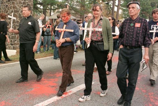 Jesuit Father Daniel Berrigan, right, and actor Martin Sheen, third from right, join the annual School of the Americas protest in 1999 at Fort Benning, Ga. Father Berrigan, an early critic of U.S. military intervention in Vietnam who for years challenged the country's reliance on military might, died April 30 at 94. CNS photo/Quirin, The Messenger)