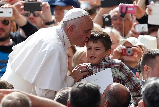 Pope Francis greets a boy carrying a tablet during his general audience in St. Peter's Square at the Vatican May 25. CNS/Paul Haring