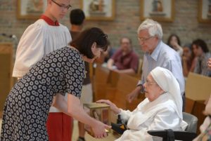 Jan Graffius, the relics' curator at Stonyhurst College in Lancashire, England, holds them for veneration by a Little Sister of the Poor June 26 at the Little Sisters' Holy Family Residence in St. Paul. Jim Bovin/For The Catholic Spirit