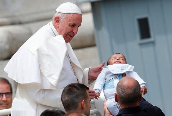 Pope Francis greets a sleeping baby as he leaves his general audience in St. Peter's Square at the Vatican June 1. CNS photo/Paul Haring