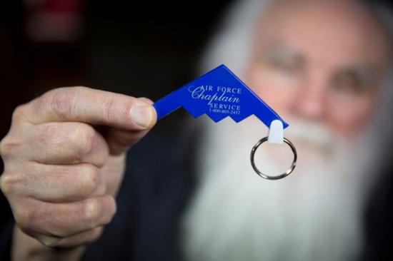 Melkite Father Emmanuel Charles McCarthy holds up an old keychain in the shape of a fighter plane representing the Air Force Chaplain Service, which he says creates an image that is not fit for any Catholic priest. This photo was taken at Father McCarthy's Brockton, Mass., home April 4. CNS photo/Chaz Muth