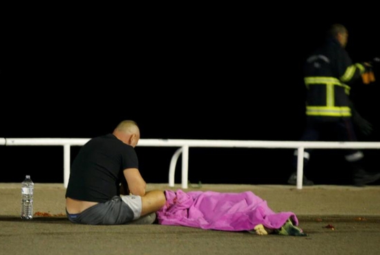 A man sits next to a body on the ground July 15 after at least 84 people were killed in Nice, France, when a truck ran into a crowd celebrating the Bastille Day national holiday July 14. CNS photoEric Gaillard, Reuters