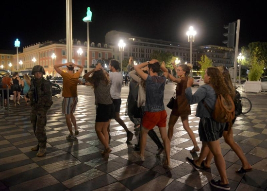 People cross the street with their hands on their heads as a French soldier secures the area July 15 after at least 84 people were killed along the Promenade des Anglais in Nice, France, when a truck ran into a crowd celebrating the Bastille Day national holiday July 14. CNS photo/Jean-Pierre Amet, Reuters