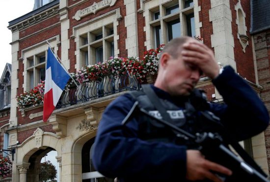 A policeman reacts as he secures a position in front of city hall after two assailants killed 84-year-old Father Jacques Hamel and took five people hostage during a weekday morning Mass at the church in Saint-Etienne-du-Rouvray, France, near Rouen July 26. CNS photo/Pascal Rossignol/Reuters
