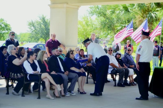 American Legion Post 93 Cmdr. Rudy Flores presents the burial flag to the family of Army veteran Jacky Eugene Gonzalez during his June 22 funeral at the Rio Grande Valley State Veterans Cemetery in Mission, Texas. Flores and other U.S. military veterans, perform these solemn duties several times a week, usually at the veterans cemetery, but they will go wherever they are needed. CNS photo/Rose Ybarra, The Valley Catholic