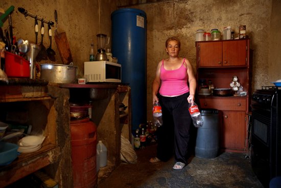 Yunni Perez holds plastic bottles used to carry water while she poses for a photo April 3 inside her home in a slum area of Caracas, Venezuela. CNS/Carlos Garcia Rawlins, EPA
