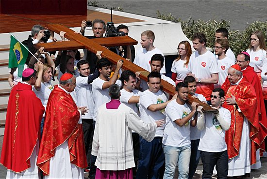 Young people from Brazil, left, pass on the World Youth Day cross to youths from Poland, right, at the conclusion of Pope Francis’ celebration of Palm Sunday Mass in St. Peter’s Square at the Vatican April 13, 2014. The next international Catholic youth gathering will be July 25-31 in Krakow, Poland. CNS/Paul Haring
