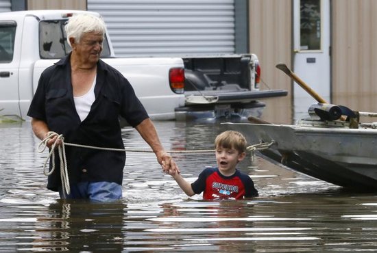 Richard Rossi and his 4-year-old great-grandson Justice wade through water Aug. 15 after their home flooded in St. Amant, La. CNS photo/Jonathan Bachman, Reuters