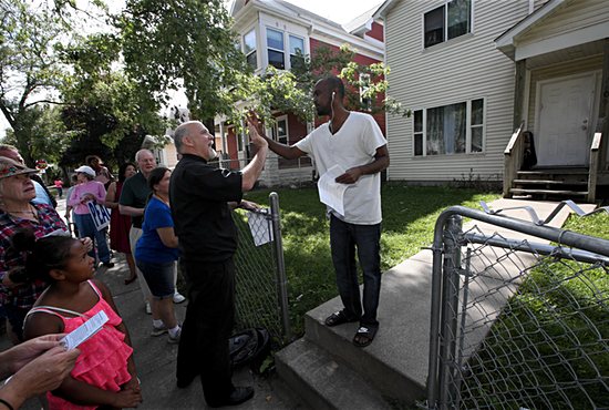 Father Paul Jarvis, center, high fives north Minneapolis resident Awil Ismail, who is Muslim, Sept. 18 as part of an effort to pray for the neighborhoods near St. Bridget, where Father Jarvis serves as associate pastor. Members of St. Bridget joined forces with members of New Creation Church, also in north Minneapolis, to pray for peace and meet residents of the neighborhood. Dave Hrbacek/The Catholic Spirit