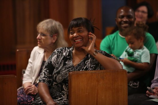 Lynette Graham of St. Peter Claver reacts to remarks by Archbishop Bernard Hebda during his homily Sept. 8. At left is Karen Johnson, wife of Deacon Fred Johnson. At right is Brendan Banteh and his daughter, Charlotte, who belong to St. Peter Claver. Dave Hrbacek/The Catholic Spirit