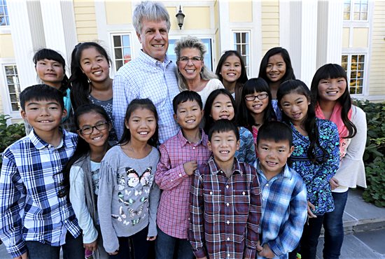 The Mulvahill family of Holy Name of Jesus in Medina includes 14 children adopted from China. Posing for a photo on the front steps of their home are, front row, from left: Joey, 8, and Luke, 7; middle row: Ben, 10, Madeline, 9, Abby, 10, Sam, 10, Melissa, 10, Jenny, 11, Anna, 10, and Ellie, 14; back row: Emma, 16, Sarah, 16, Jim, Jean, Mia, 14, and Ava, 11. Dave Hrbacek/The Catholic Spirit