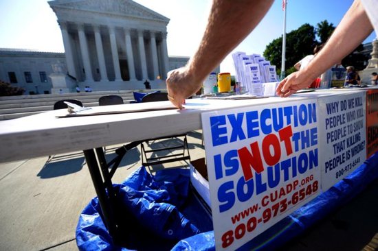 A member of the Abolition Action Committee hangs a sign in front of the Supreme Court in Washington during a 2008 vigil to abolish the death penalty. CNS photo/Shawn Thew, EPA
