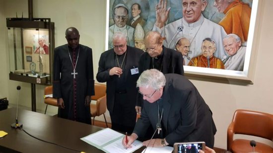 Archbishop Jean-Claude Hollerich, president of the Commission of the Bishops' Conferences of the European Union, signs a joint statement Oct. 26 at the Vatican's Sala Marconi calling on the international community to take immediate action against climate change. Also pictured in the signing are Also pictured in the signing are Archbishop Gabriel Mbilingi of Lubango, president of the Symposium of Episcopal Conferences of Africa and Madagascar, left, Cardinal Jose Luis Lacunza Maestrojuan of David, Panama, president of Latin American bishops' council's economic committee, and Cardinal Oswald Gracias of Mumbai, India, president of the Federation of Asian Bishops' Conferences. 