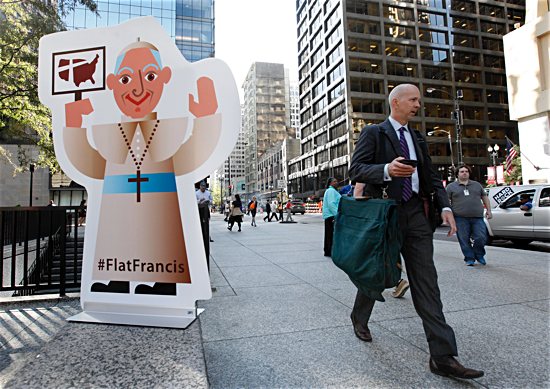 Commuters pass a life-size “Flat Francis” in Daley Plaza in Chicago in 2015. Chicago-based Catholic Extension created the Flat Francis social media campaign to officially welcome Pope Francis on his first visit to America. 