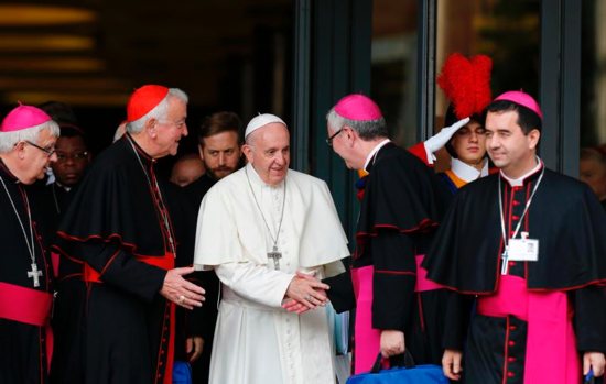 Pope Francis greets Bishop Mark O'Toole of Plymouth, England, as he leaves a session of the Synod of Bishops on young people, the faith and vocational discernment at the Vatican Oct 5. Next to the pope is Cardinal Vincent Nichols of Westminster, England.