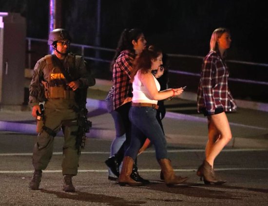Women who fled from the shooting at the Borderline Bar and Grill in Thousand Oaks, Calif., pass by a sheriff's deputy Nov. 8 after a gunman killed at least 13 people. The gunman, who opened fire without warning late Nov. 7, was found dead inside the establishment, authorities said.