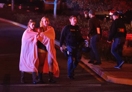 Two women draped in blankets leave the area near the Borderline Bar and Grill in Thousand Oaks, Calif., Nov. 8 after a gunman killed at least 13 people. The gunman, who opened fire without warning late Nov. 7, was found dead inside the establishment, authorities said.