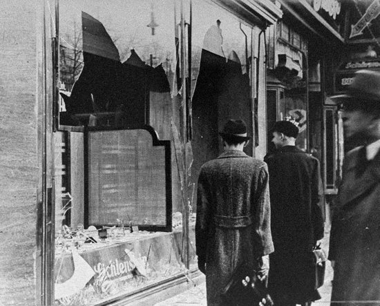 Germans pass by the broken shop window of a Jewish-owned business in Berlin that was destroyed in 1938 during Kristallnacht, or the "Night of Broken Glass." That year, from Nov. 9 to Nov. 10, Nazis in Germany torched synagogues and vandalized Jewish homes and schools. 