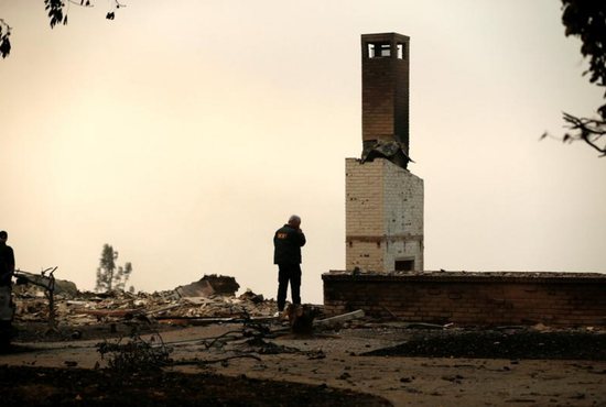 A Butte County Sheriff deputy surveys a home Nov. 11 that was destroyed by the Camp Fire in Paradise, Calif. Catholic schools in the Diocese of Sacramento are opening their doors to all students displaced by the fires to attend their schools tuition free for the rest of the year. 