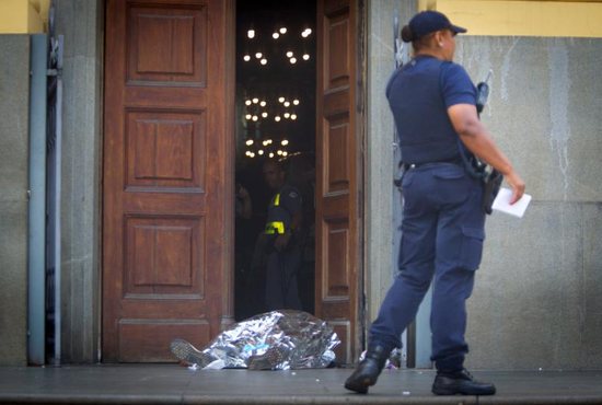 A police officer stands next to a body at the scene of a shooting Dec. 11 at the Metropolitan Cathedral in Campinas, Brazil. Police said Euler Fernando Grandolpho opened fire in the cathedral, killing at least four people and injuring several others before the 49-year-old turned the gun on himself after being shot by police. 