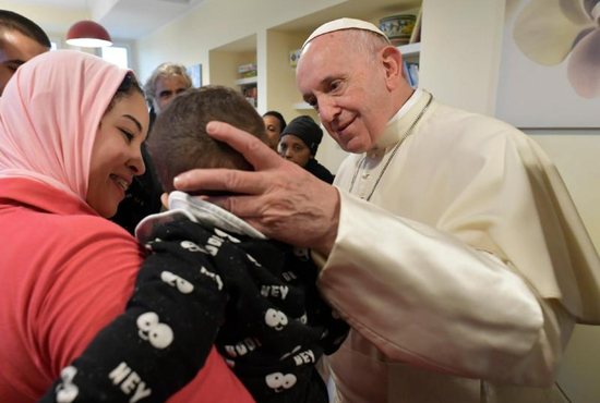 Pope Francis greets a child as he visits poor, sick people at a center run by the CasAmica Onlus organization on the outskirts of Rome Dec. 7. The visit continued the pope's tradition of doing Friday works of mercy.