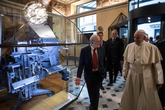 Pope Francis and Virman Cusenza, director of Il Messaggero daily newspaper, walk past a Linotype machine on display during a visit to the newspaper's office in Rome Dec. 8.