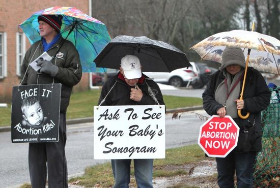 Pro-life advocates gather in silent witness near the entrance of a Planned Parenthood center in 2018 in Smithtown, N.Y. A proposed abortion law for New York state that would allow more health practitioners to provide abortion and remove all state restrictions on late-term abortions "is not progress" as lawmakers argue, said New York's Catholic bishops.