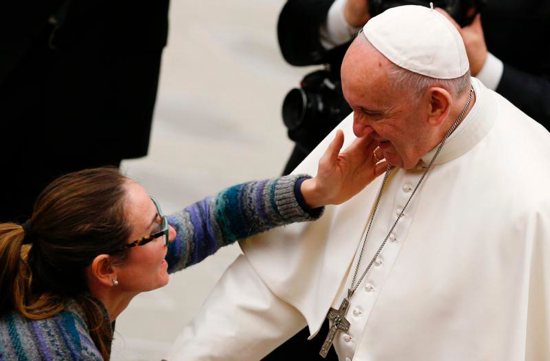 A woman touches Pope Francis' face during his general audience in Paul VI hall at the Vatican Jan. 16. 