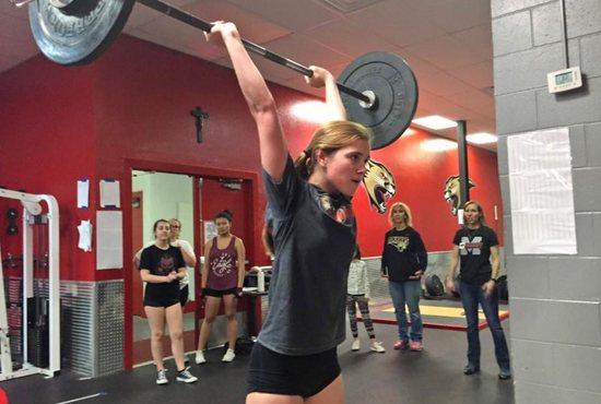 Grace Dickinson, a senior at Cardinal Mooney High School in Sarasota, Fla., performs a dead lift to an overhead press with 95 pounds as her coaches observe her Dec. 19, 2018. This is the inaugural year for the girls weightlifting team at the Florida Catholic school.